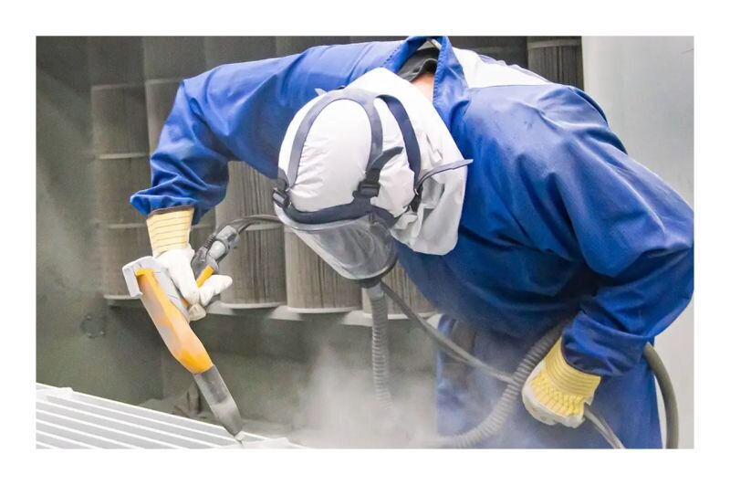 Worker applying powder coating to grain system part
